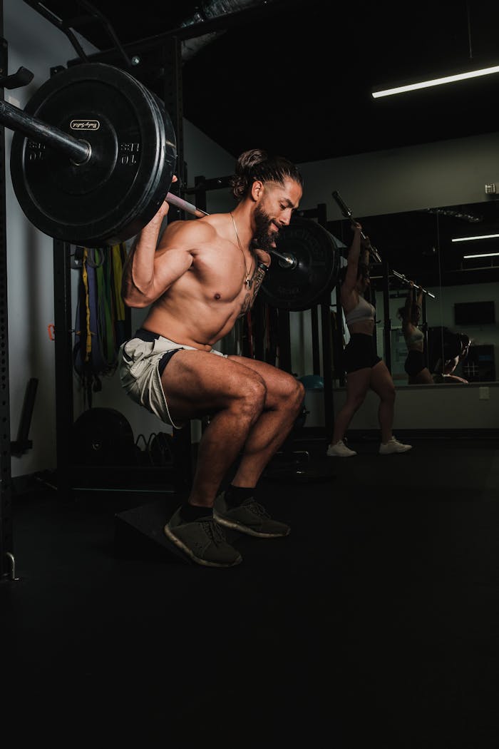 services-02 A shirtless man lifts weights during an intense gym workout, showcasing strength and fitness.